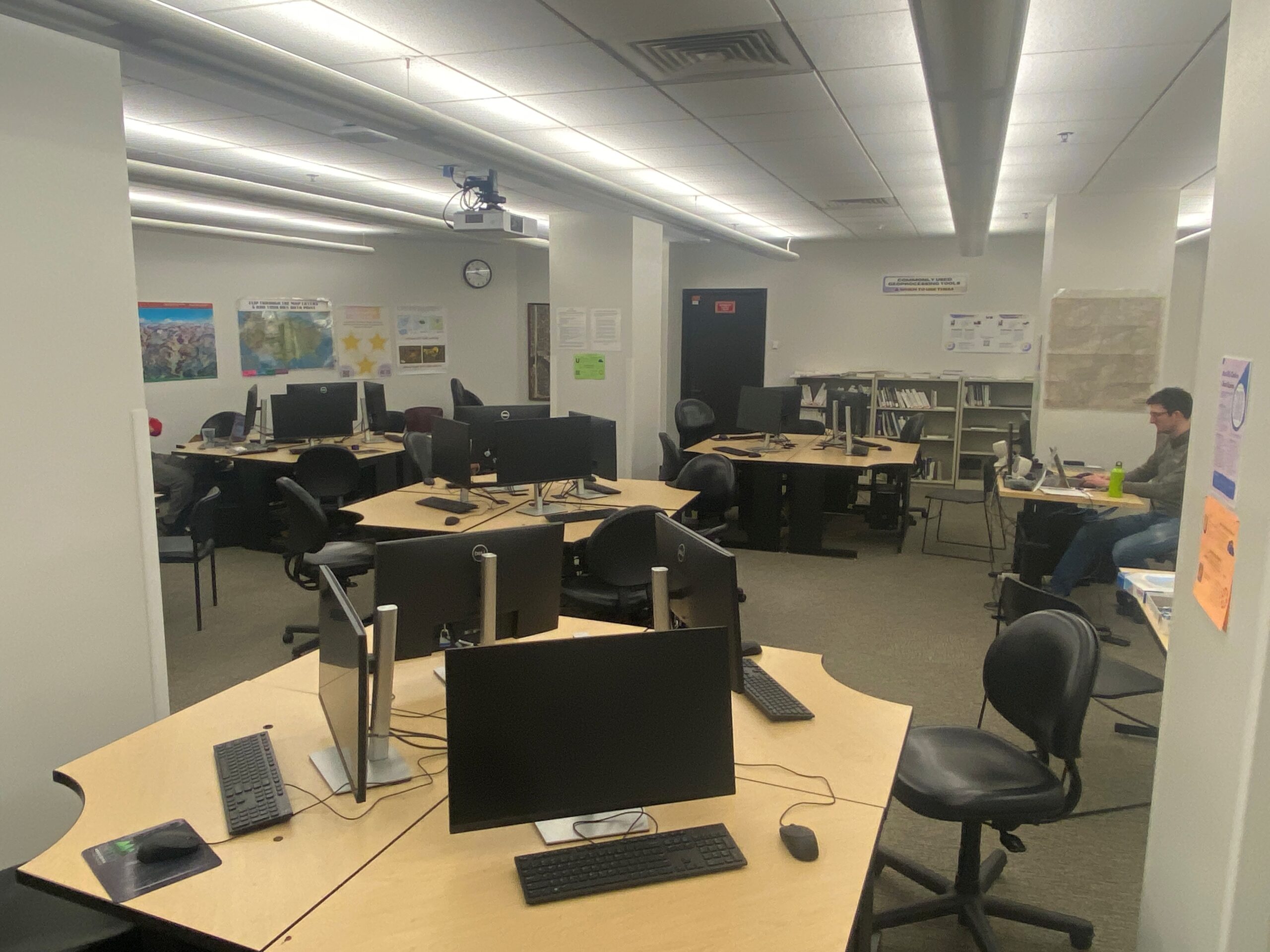 Gis Lab. Several group tables with monitors, keyboards, and desk chairs.