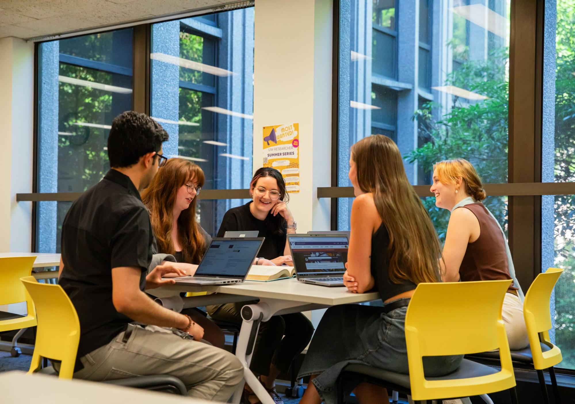 Students with laptops working together around a table