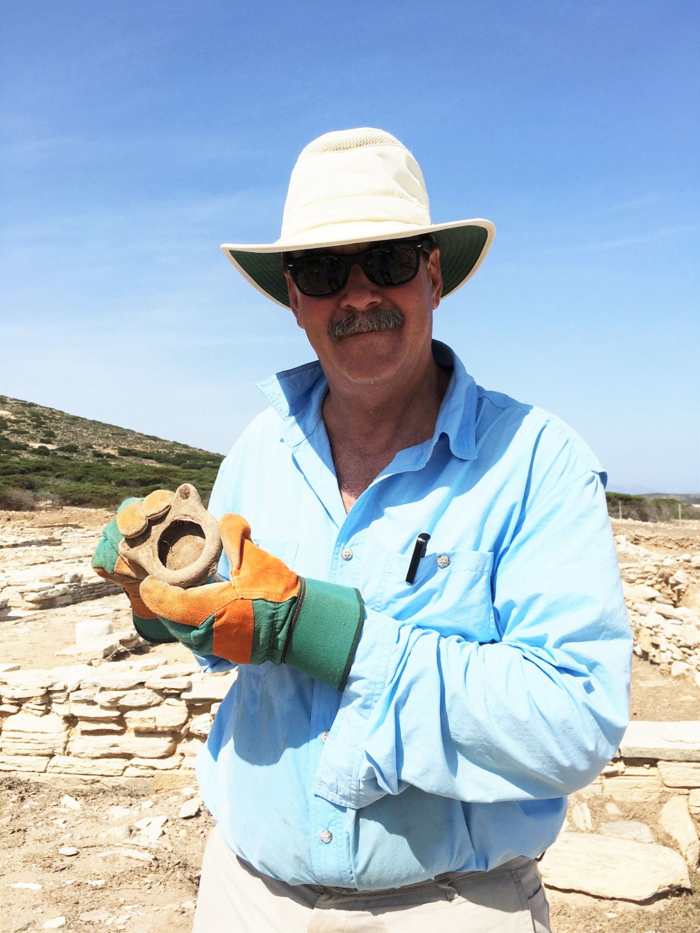 Man in a hat holding an ancient lamp he dug up.