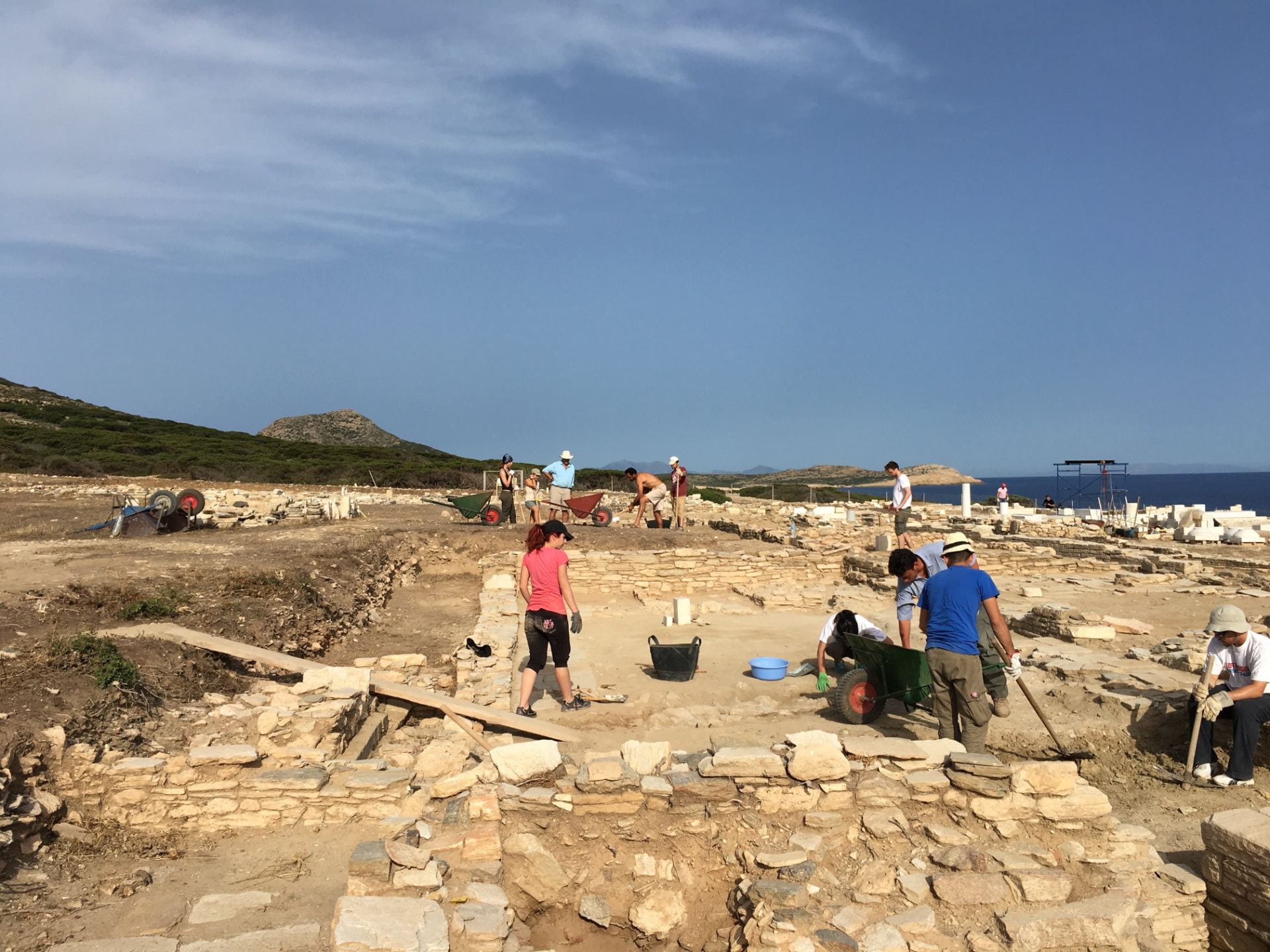 Excavation site with people examining and removing stones from the ground.